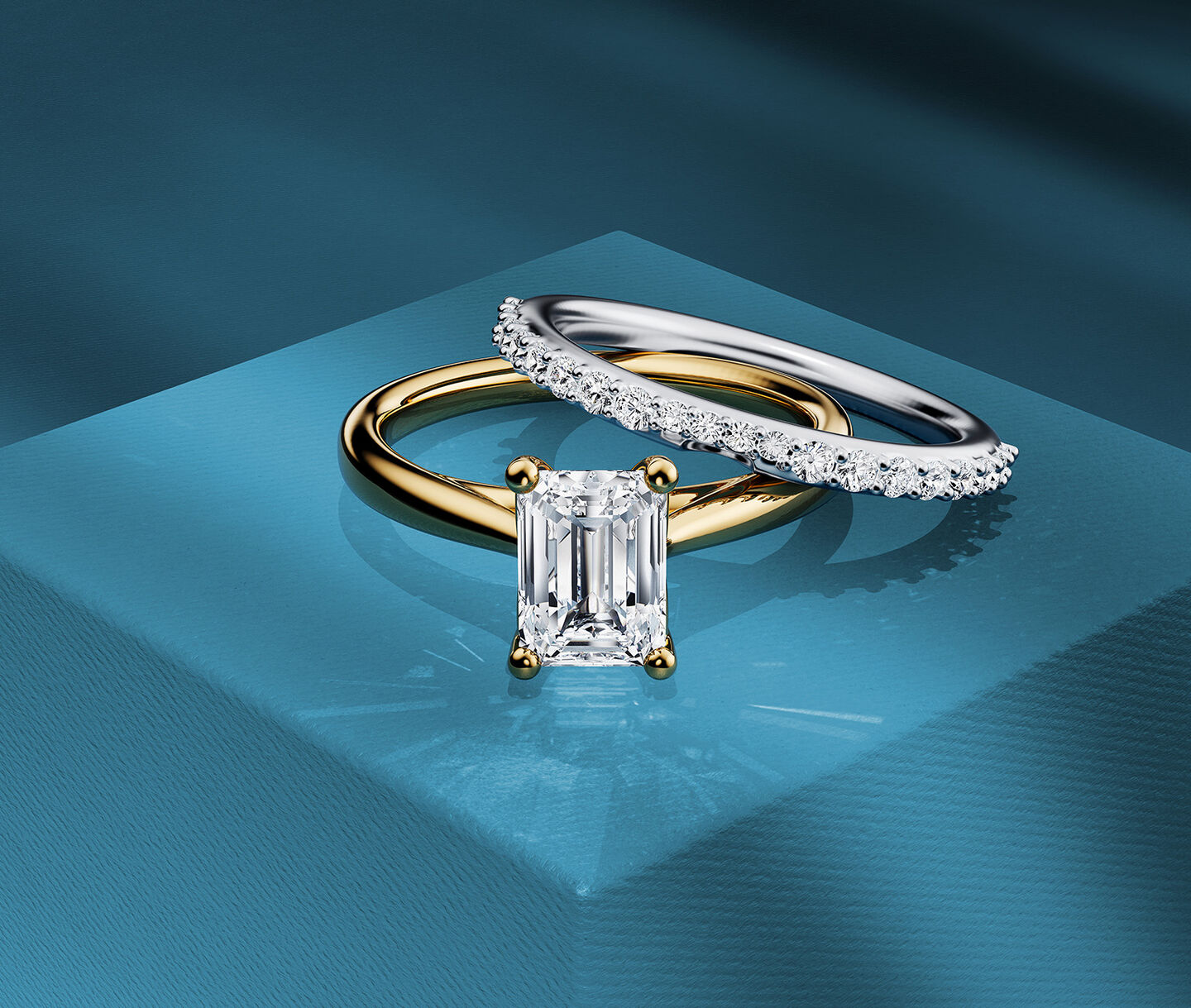A Birks emerald-cut diamond engagement ring and eternity band on a blue background.